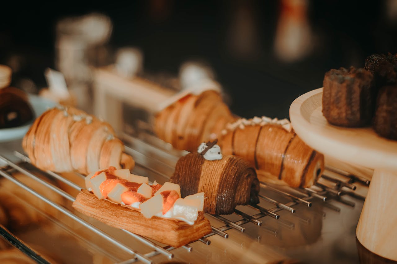 Gourmet pastries including croissants and dessert bars beautifully displayed on a rack.